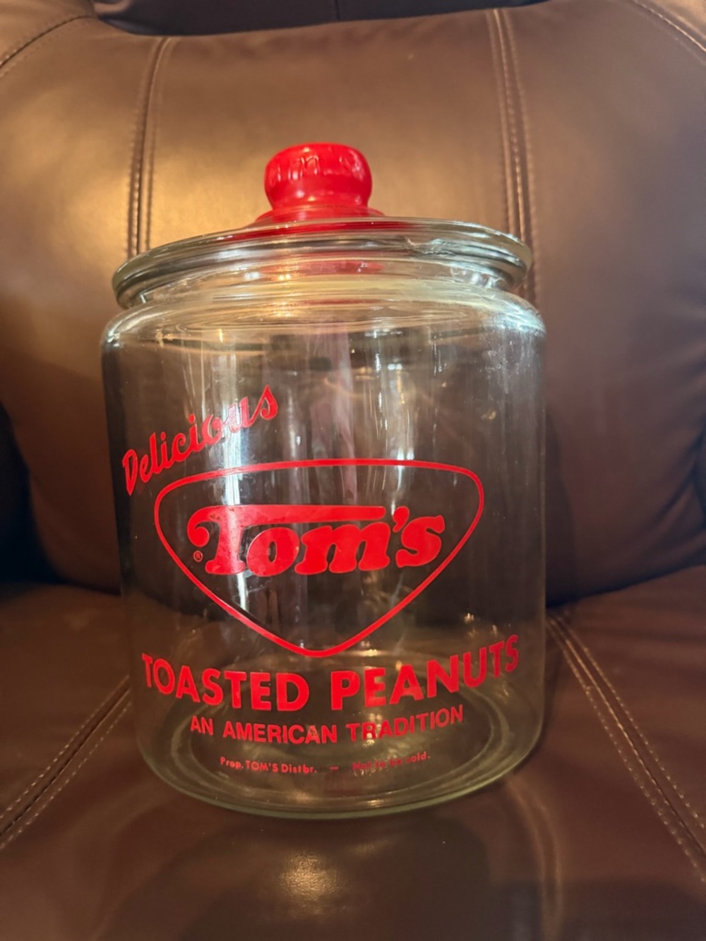 Toms Clear Glass Jar with Red Logo and Red Lid Knob has small chip out of top.